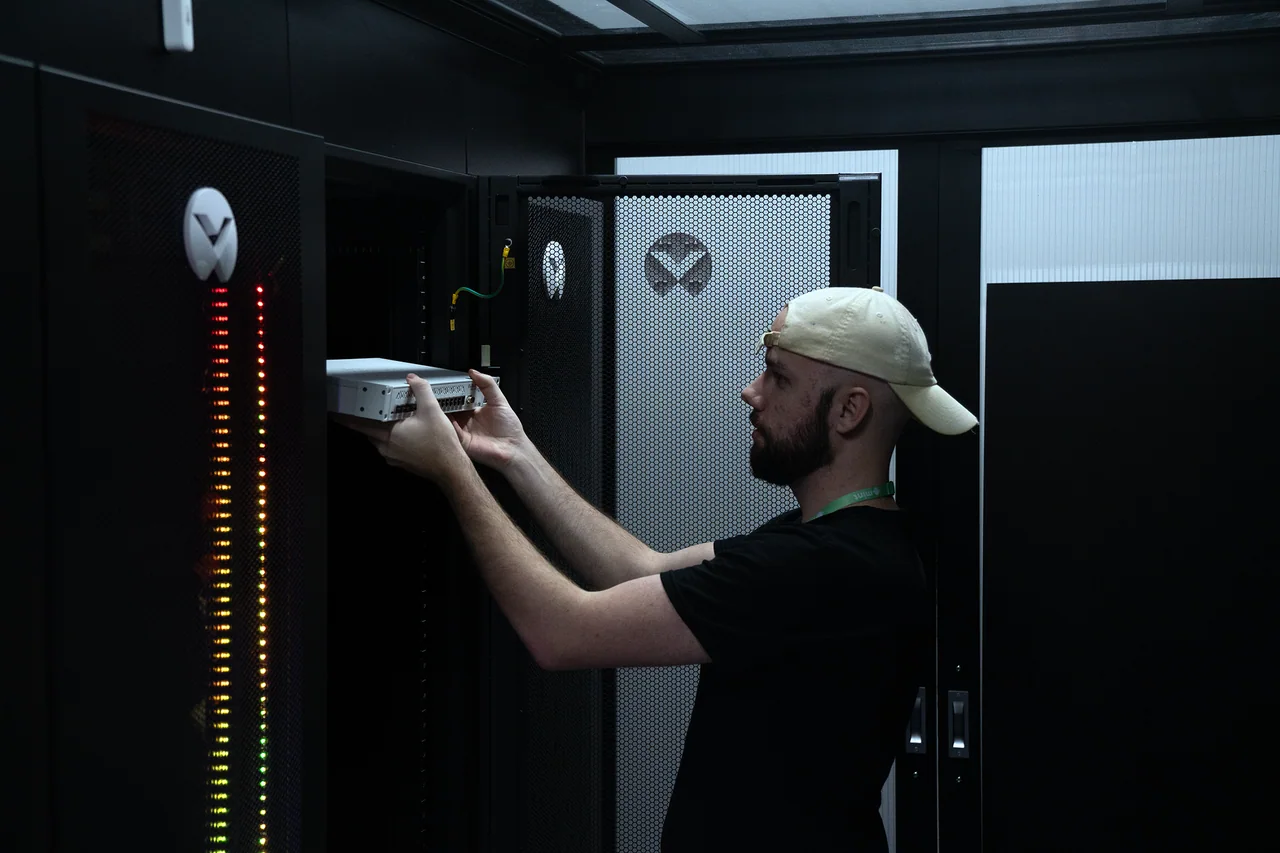 A Mint technician fitting a network switch into a rack in a data centre