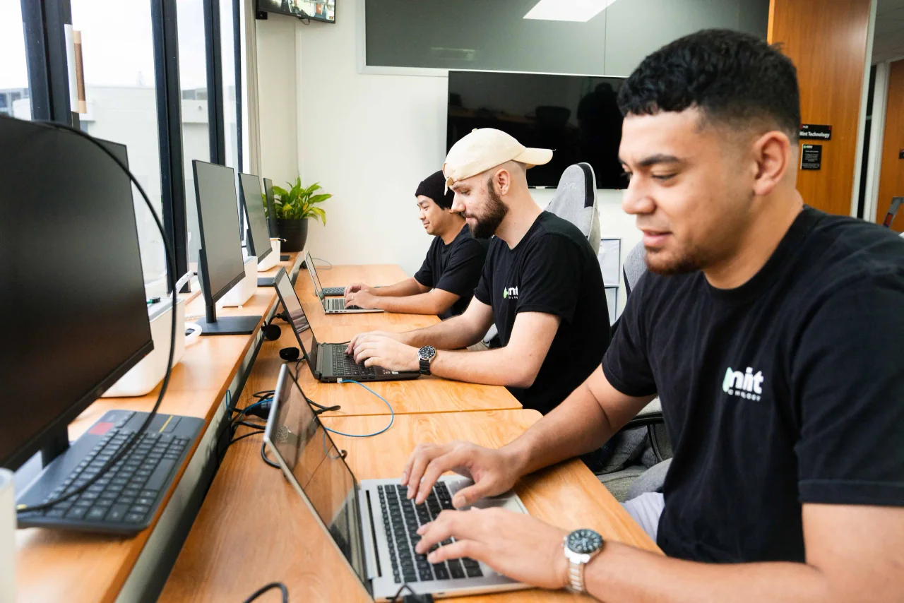 Mint technicians working at laptops side by side in the Birkenhead office