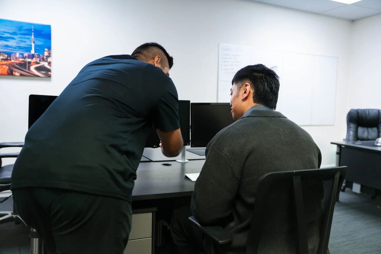 A Mint technician helping a colleague at a workstation