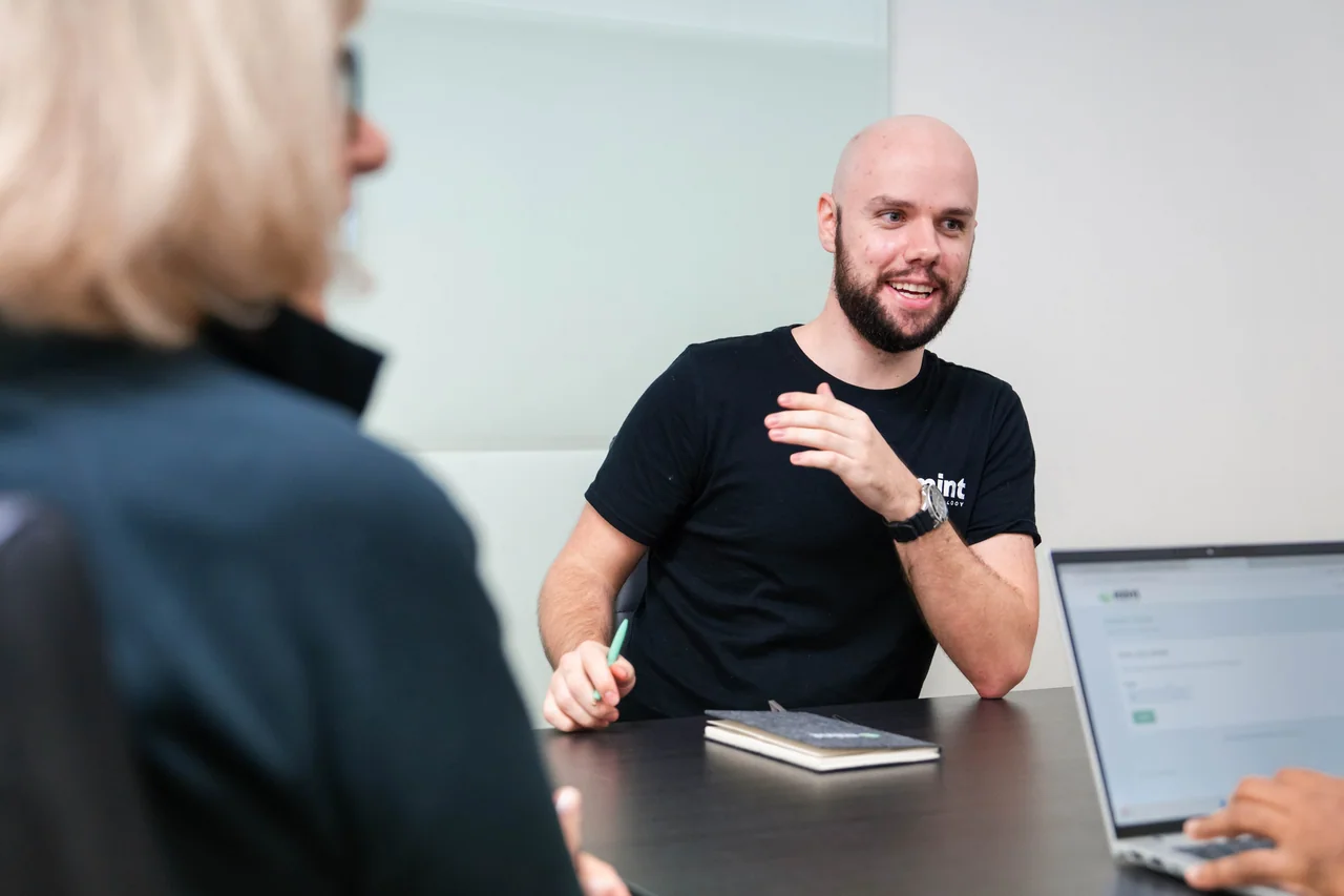 A Mint team member talking with a client across a meeting table