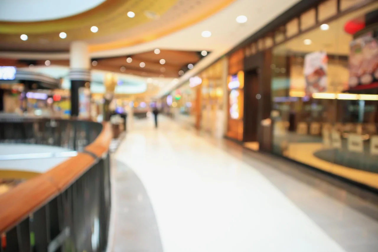 A bright shopping centre walkway with shops on either side